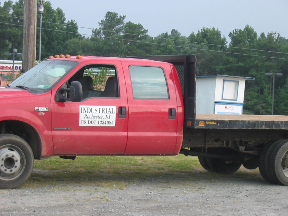 Red crew cab flatbed truck side view with "INDUSTRIAL Rochester, NY US DOT 1234085" decal