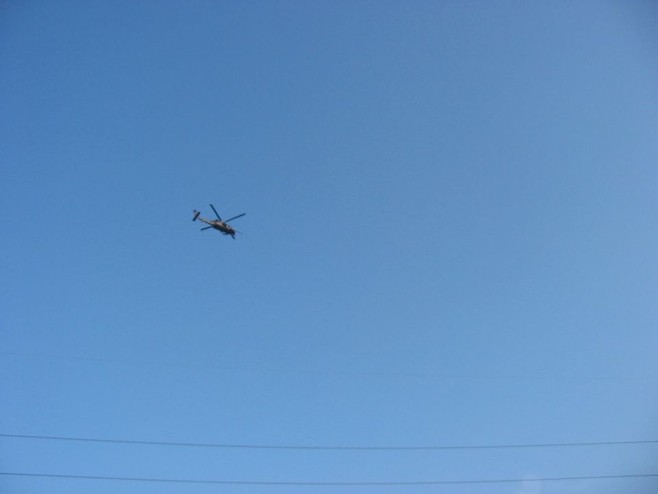 Helicopter flying in a clear blue sky with power lines in the foreground