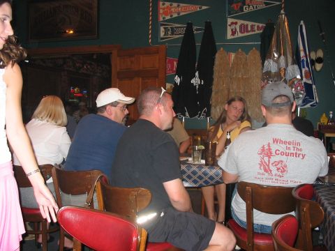 1988 Ford Bronco - A group of people are gathered around tables inside a dimly lit establishment, possibly a bar or restaurant.