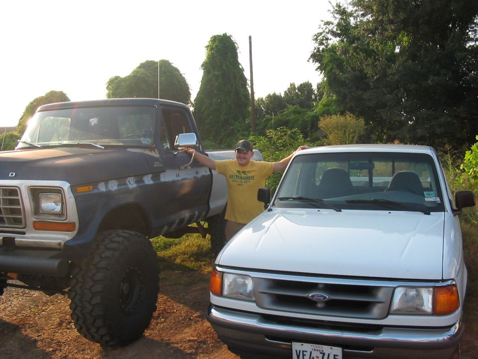 Dark blue lifted 1980 Ford pickup next to white compact pickup