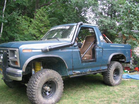 1986 Ford Bronco - This modified SUV features a snorkel and roll cage, with visible text on the windshield banner.