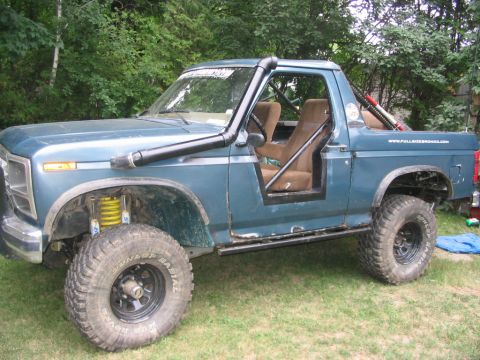 1986 Ford Bronco - This modified Ford Bronco features a snorkel and roll cage, with a website visible on the tailgate.