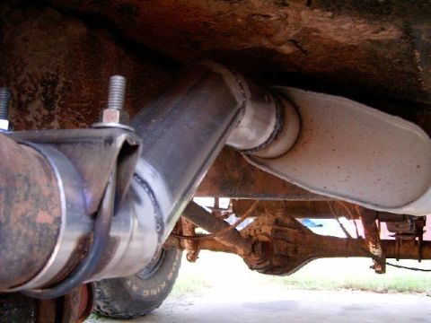 1978 Ford Bronco - Close-up view of a vehicle's exhaust system and rear axle, with visible text from a website.