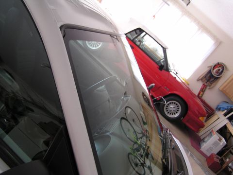 1990 Ford Mustang - A red 1990 Ford Mustang convertible is parked in a garage, with a white car beside it. Bicycles are visible in the reflection.