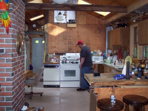 2001 Ford Crown Victoria - A man stands at a stove in a rustic kitchen with exposed wood and brick elements.