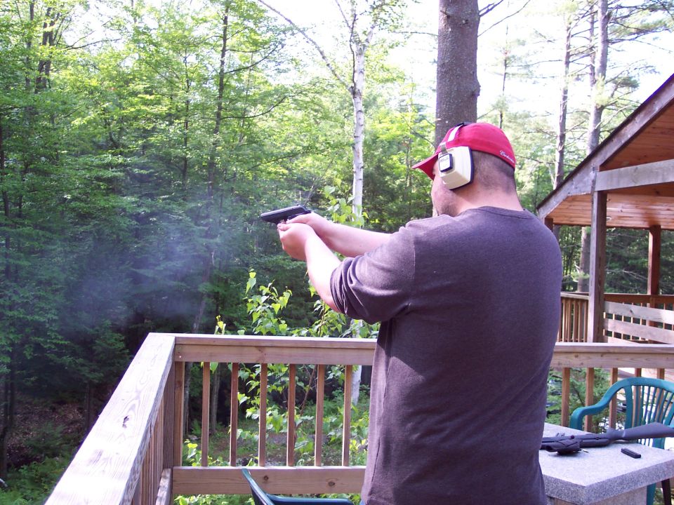 Man firing handgun on wooden deck