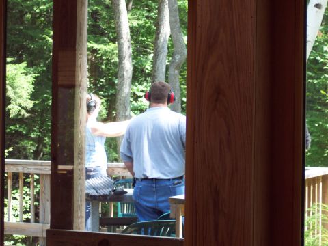 2001 Ford Crown Victoria - People practice shooting outdoors on a wooden deck surrounded by trees.
