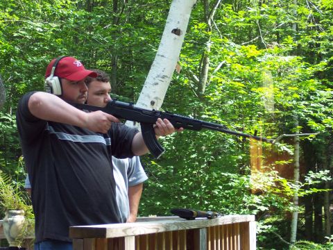 2001 Ford Crown Victoria - Two men are at an outdoor shooting range, one aiming a rifle.