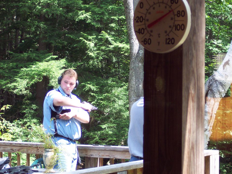 Man wearing headphones and holding a handgun on a wooden deck