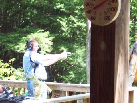 2001 Ford Crown Victoria - A person practices shooting a handgun outdoors on a sunny day, with a thermometer showing the temperature.