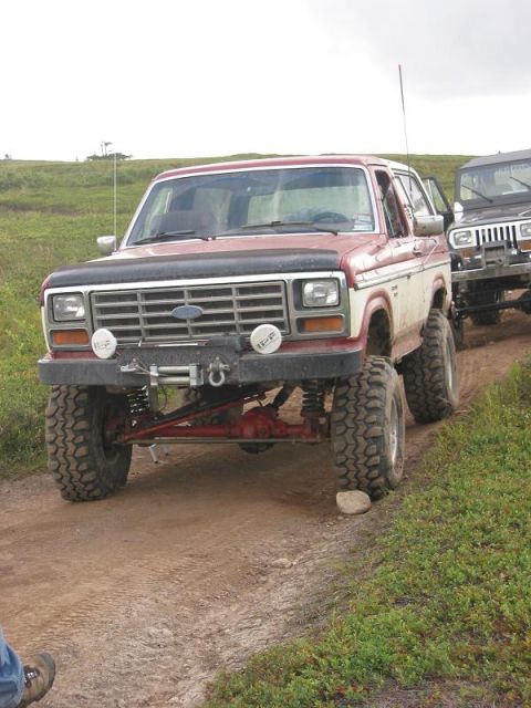 1985 Ford Bronco - This lifted Ford Bronco is equipped with off-road tires and a winch, ready for adventure on a dirt path.
