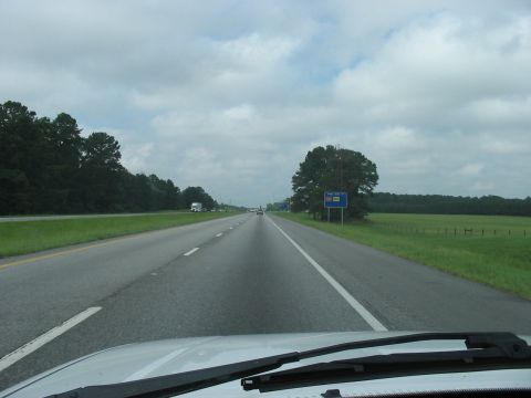 1988 Ford Bronco - View from inside a vehicle driving on a highway under a cloudy sky.