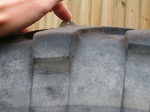 1991 Ford Bronco - A coin is placed on a tire tread to show its depth.