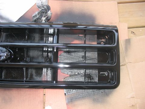 1988 Ford Bronco - Grille being spray painted black, set up on cardboard and wood.