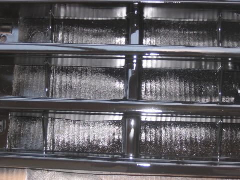 1988 Ford Bronco - A close-up view of a vehicle's black grille, showing its textured inner sections and shiny horizontal bars.