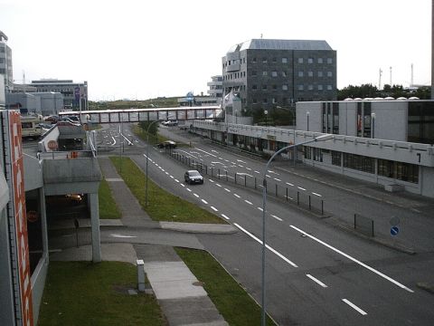1996 Ford Bronco - A view of an airport road with a pedestrian bridge connecting buildings, and several cars driving by.