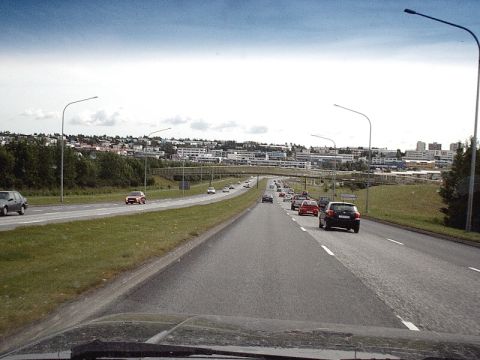 1996 Ford Bronco - Highway traffic moves towards a city skyline under a partly cloudy sky.