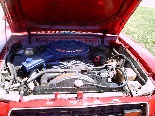 1978 Ford Mustang II - The engine bay of a red vehicle is shown, a blue air cleaner and visible engine components. A watermark from Supermotors.net is present.