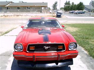 1978 Ford Mustang II - Front view of a red 1970s Ford Mustang II, likely from the mid-1970s, a prominent hood scoop and racing stripes.