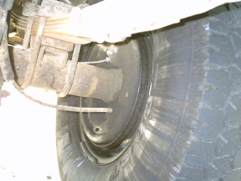 1984 Ford Bronco - This image shows the rear suspension and tire of a vehicle, focusing on the brake drum and leaf springs.