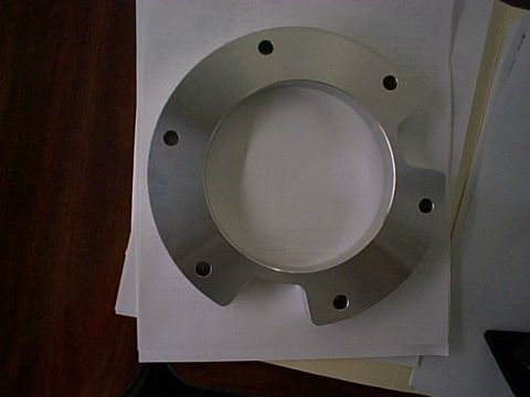1994 Ford Bronco - A metal flange with a circular opening and six bolt holes is shown on a desk.