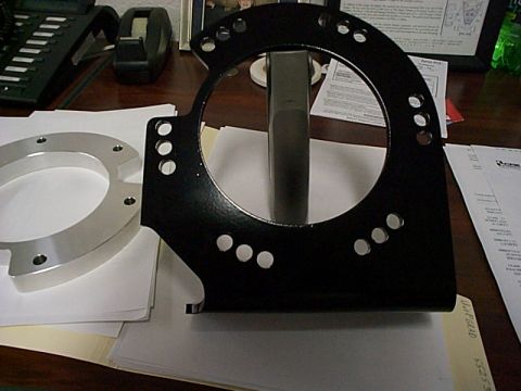 1994 Ford Bronco - Two metal adapter parts are shown on a desk, one black and one silver, with documents in the background.