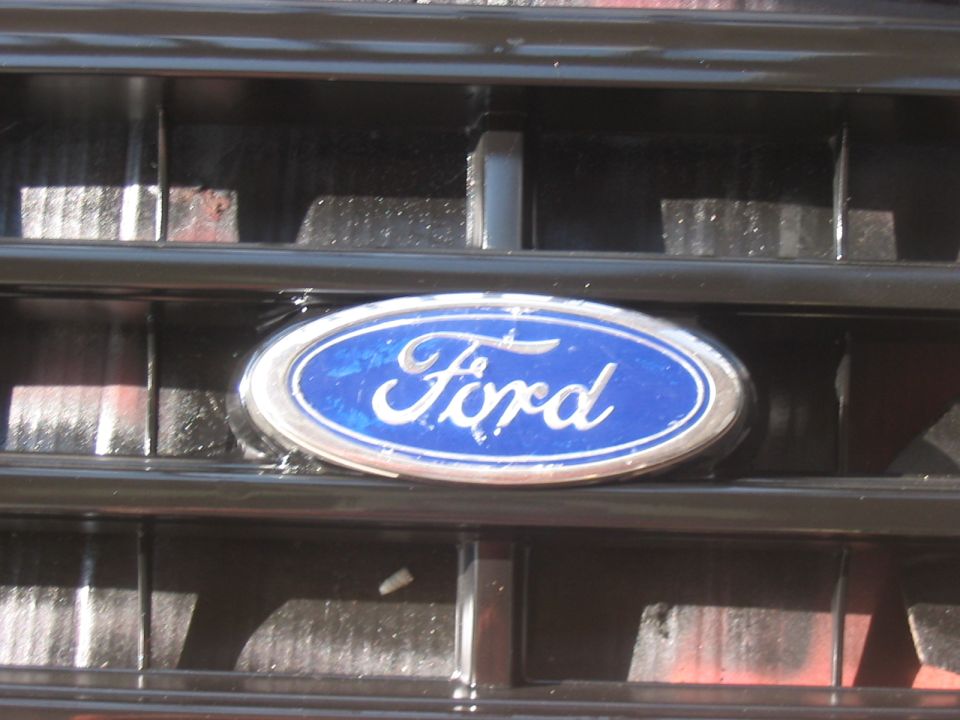 Close-up of a blue Ford oval emblem on a black grille