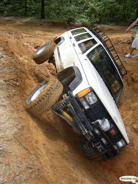 1984 Ford Bronco - A Jeep gets stuck on a steep, muddy incline during an off-road excursion.