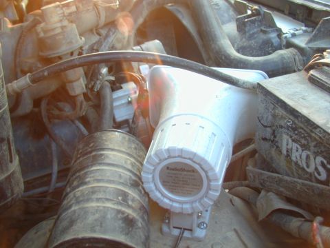 1988 Ford Bronco - Close-up of an engine bay showing a RadioShack siren and various engine parts.