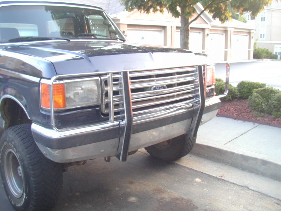 Dark blue lifted Ford 4x4 with chrome brush guard parked in a residential driveway