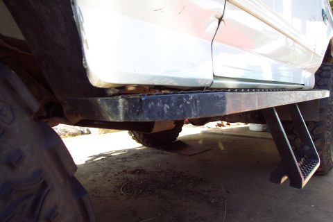 1996 Ford Bronco - Aftermarket rock slider step boards are visible on the side of a white SUV, with a portion of the tire in the foreground.