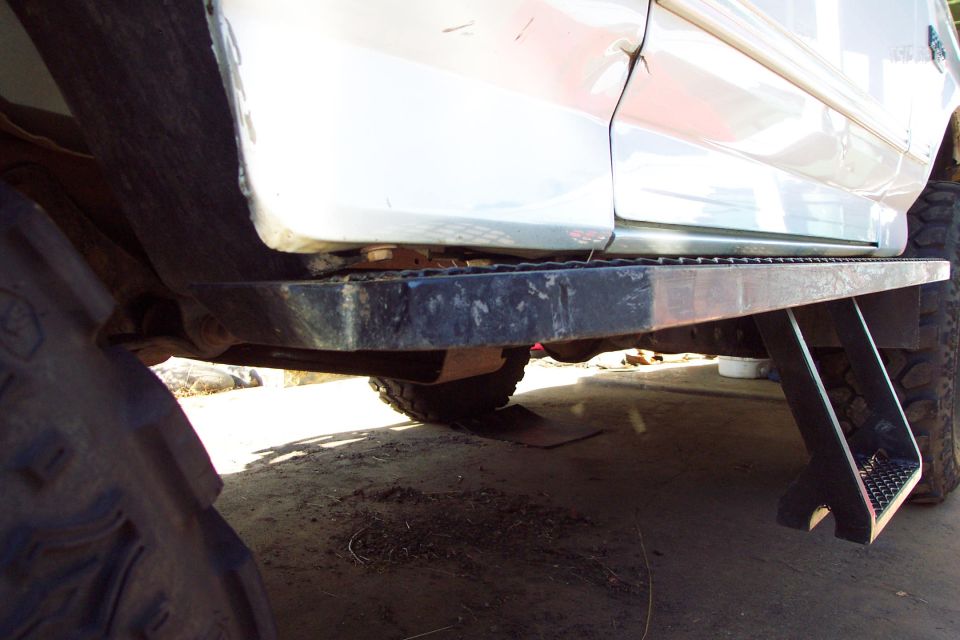 Underside view of white Bronco showing running board and diamond-plate step