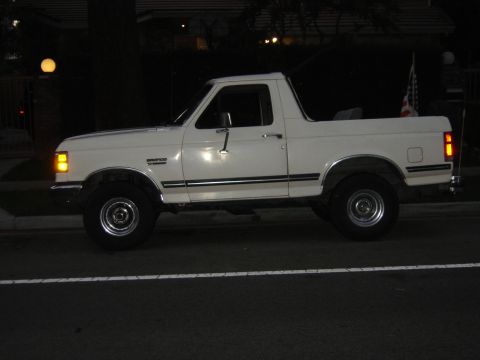 1988 Ford Bronco - A white Ford Bronco is seen from the side at night, parked on a street.
