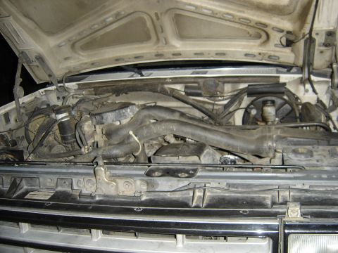 1988 Ford Bronco - The engine bay of a 1988 Ford Bronco shows various hoses, the fan, and other engine components.