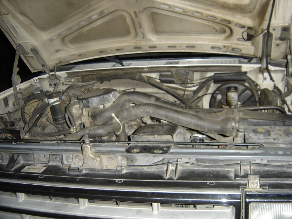 Dusty engine bay of a white Ford truck viewed from the front with hood open