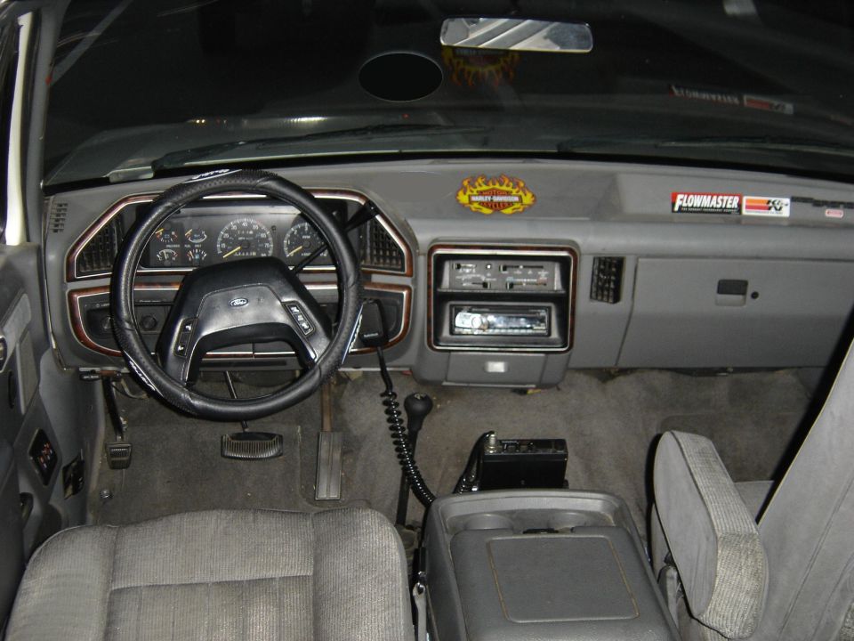 Gray Ford truck interior with steering wheel, gauges, stereo, shifter and cloth seats