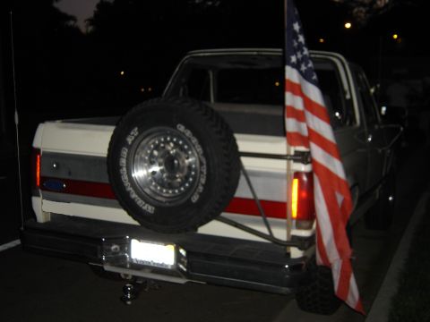 1988 Ford Bronco - Rear view of a 1987 Ford Bronco showing its spare tire and an American flag.