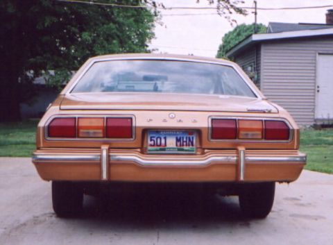 1978 Ford Mustang II - The rear of a gold 1978 Ford Mustang II is shown parked in front of a garage.