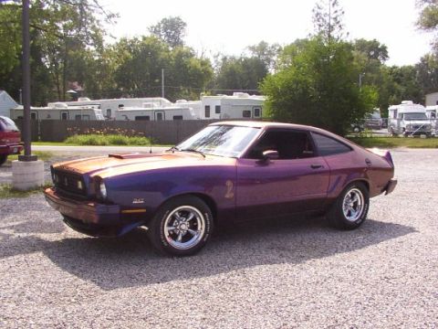 1978 Ford Mustang II - A purple 1978 Ford Mustang II coupe is parked on a gravel lot.