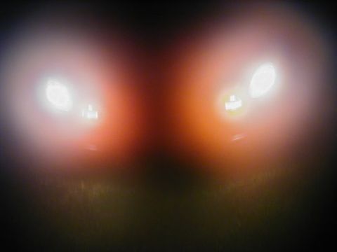 1997 Ford Taurus - The headlights of a vehicle are visible at night, casting a bright light and a reddish glow.