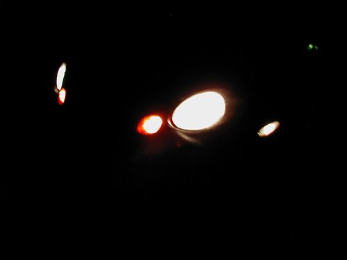 car lights on at night, some white headlights and red taillights visible