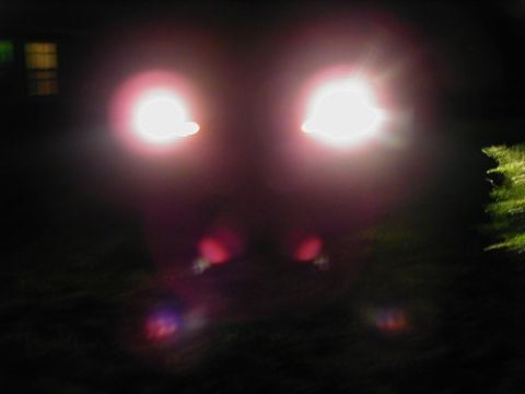 1997 Ford Taurus - The bright headlights obscure most of the vehicle's details, making identification difficult.