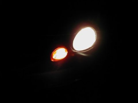1997 Ford Taurus - Illuminated headlight and amber turn signal against a black background. Text at the bottom reads SUPERMOTORS.