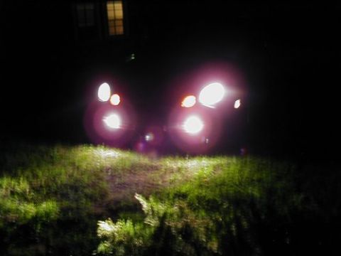 1997 Ford Taurus - Headlights of a 1997 Ford Taurus shine brightly at night, illuminating the grassy area in-field.
