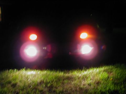 1997 Ford Taurus - The rear lights of a 1997 Ford Taurus are illuminated at night, casting a glow on the grass in front.
