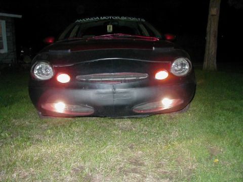 1997 Ford Taurus - Front view of a 1997 Ford Taurus with its lights on, parked on grass at night.