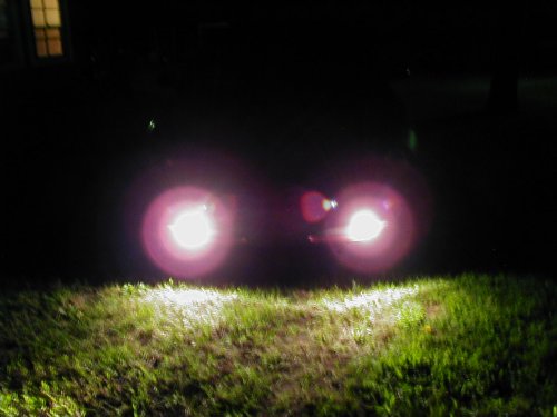 car headlights shining on grass at night