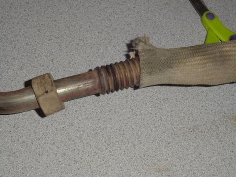1987 Ford Bronco - Close-up of a damaged exhaust pipe section with its heat shield fraying.