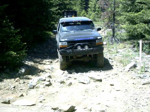 1995 Ford Bronco - This black 1995 Ford Bronco navigates a challenging rocky trail, its off-road capabilities.