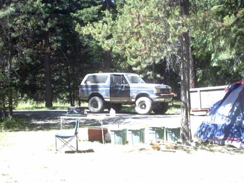 1995 Ford Bronco - A Ford Bronco is parked at a campsite, with a tent and camping gear visible.